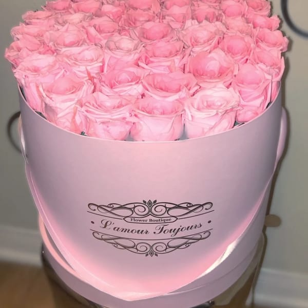 Round pink hat box filled with tightly packed light pink roses