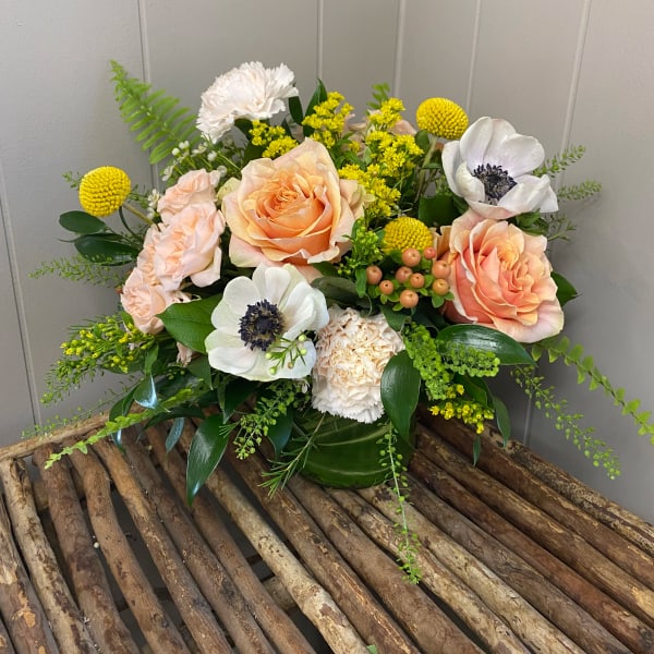 Peach roses and white anemones in a green vase