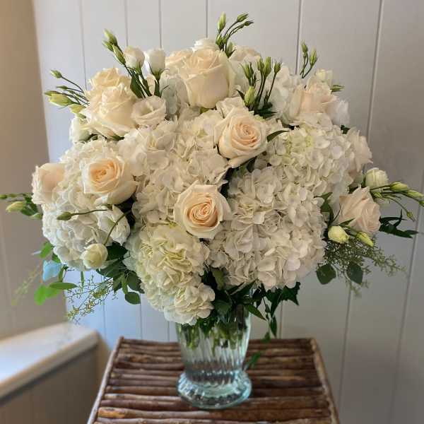Cream roses and white hydrangeas in a clear glass vase