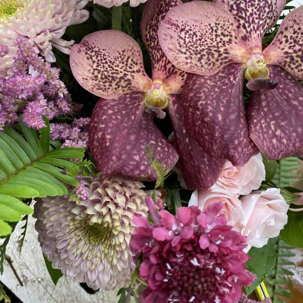 Bouquet with pink orchids, pale chrysanthemums, and a large pink gerbera daisy