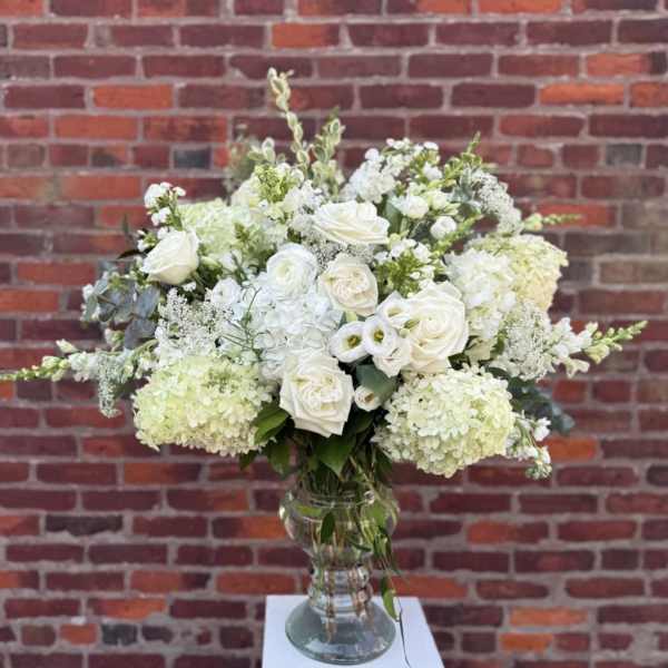 White roses and hydrangeas arranged in a clear glass vase