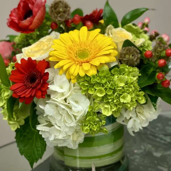 Mixed bouquet with gerbera daisies, hydrangeas, and roses in a glass vase