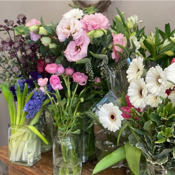 Assorted bouquets of pink, white, and purple flowers in glass vases