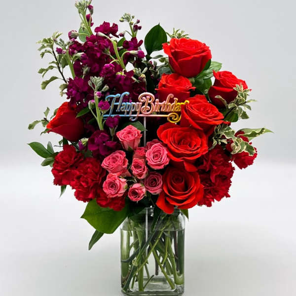 Bouquet of red and pink roses with purple flowers in a glass vase