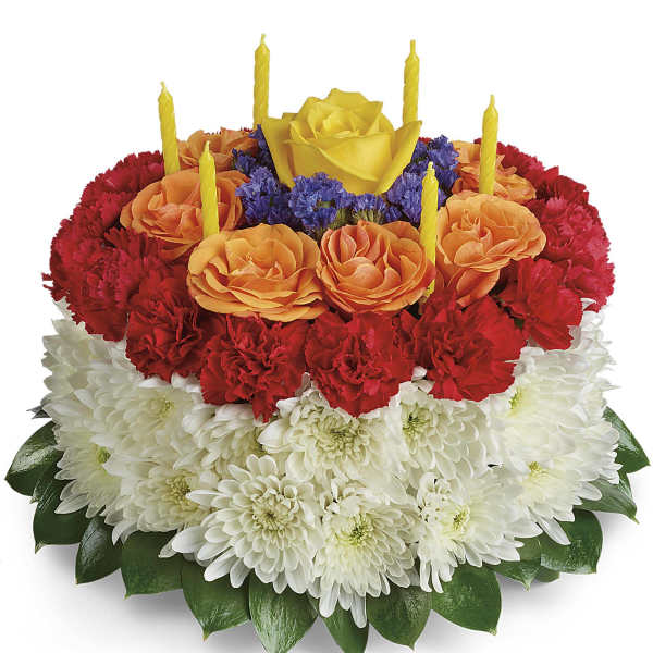Round floral cake with red, orange, and white flowers and yellow candles