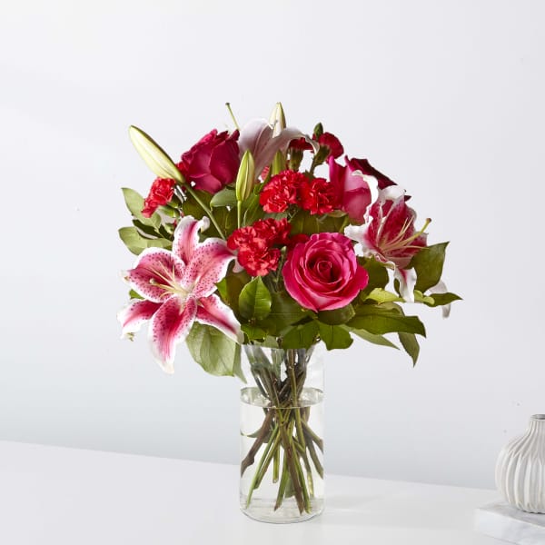 Pink roses and lilies arranged in a clear glass vase