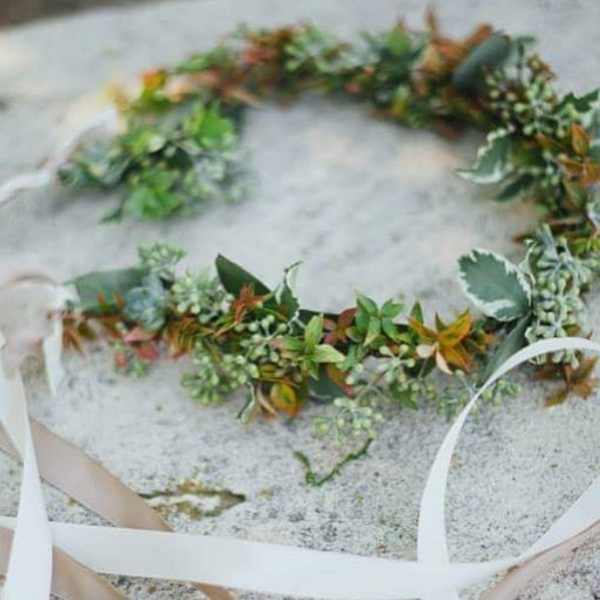Floral crown with green and rust-colored foliage on a light ribbon