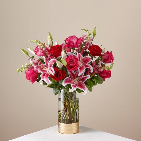 Pink and red roses with lilies in a clear glass vase