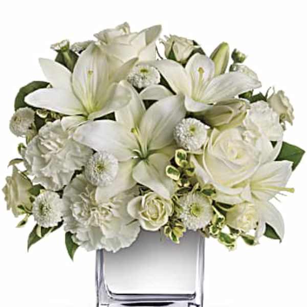 White floral arrangement in a clear square vase