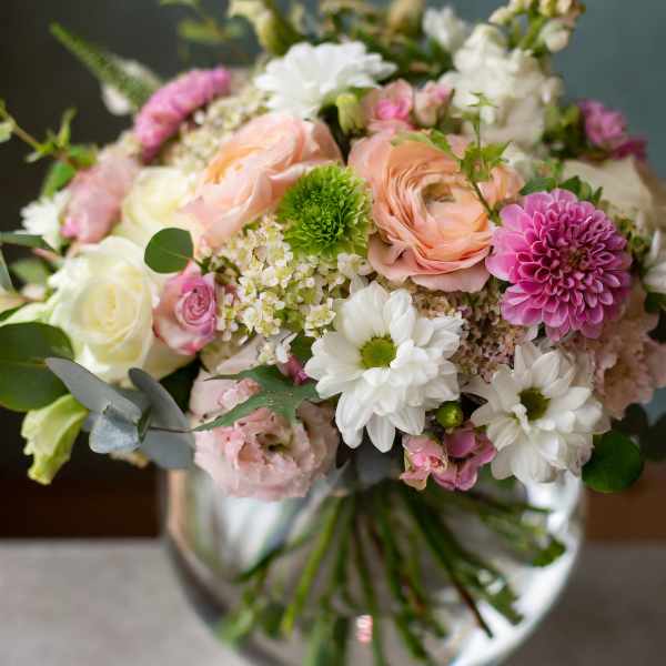 Mixed bouquet of pink, white, and peach flowers in a glass vase
