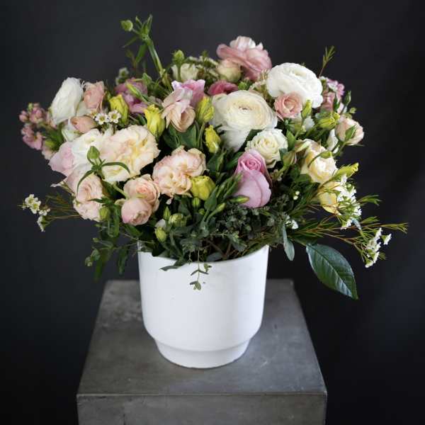 Pastel bouquet of roses and ranunculus in a white vase