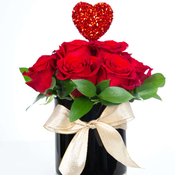Red roses in a black vase with a glittery heart topper and gold ribbon