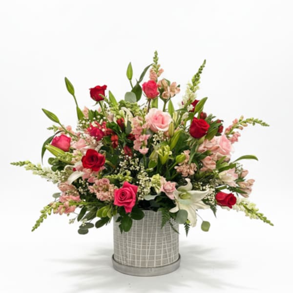 Mixed pink and red flower arrangement in a gray vase