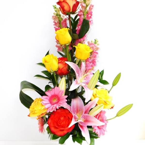 Tall bouquet of roses, lilies, and pink flowers in a white vase