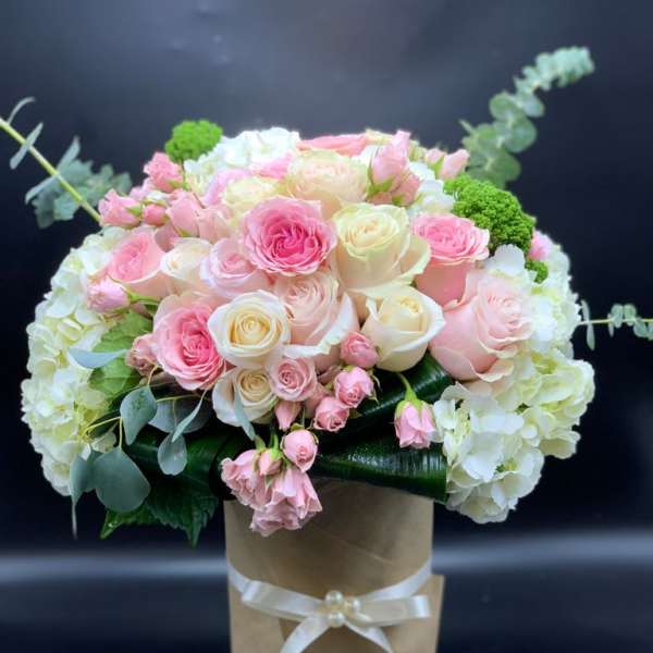 Pink and white rose bouquet in a brown paper wrap with a ribbon