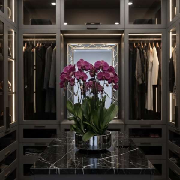 Pink orchids in a silver bowl on a black marble table