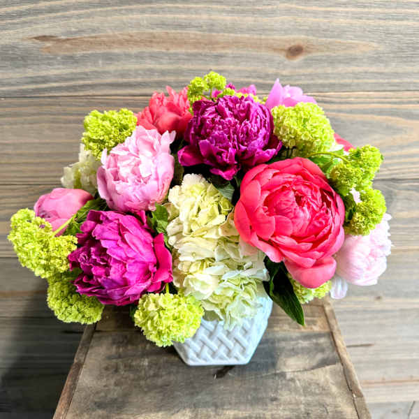 Pink and magenta flowers arranged in a white vase
