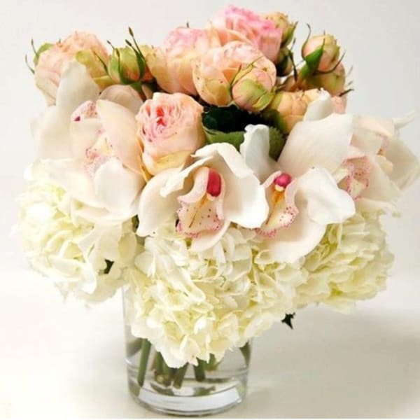 White orchids and pale pink roses in a clear glass vase