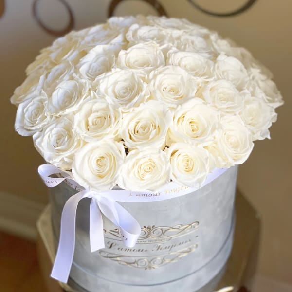 Round bouquet of white roses in a white hatbox with a ribbon