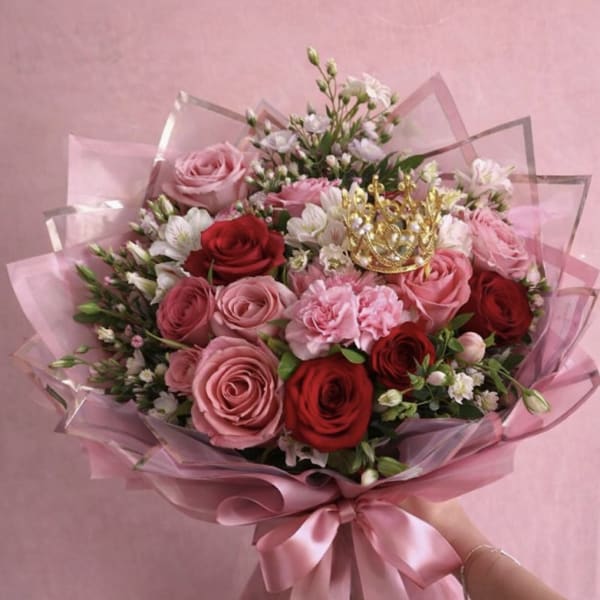 Pink and red rose bouquet wrapped in pink paper with a satin ribbon