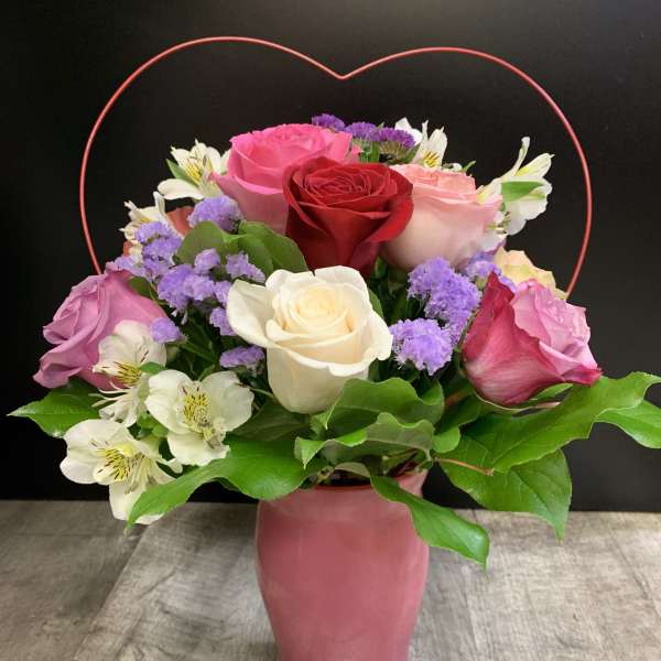 Mixed roses and white alstroemeria in a pink vase with a heart handle