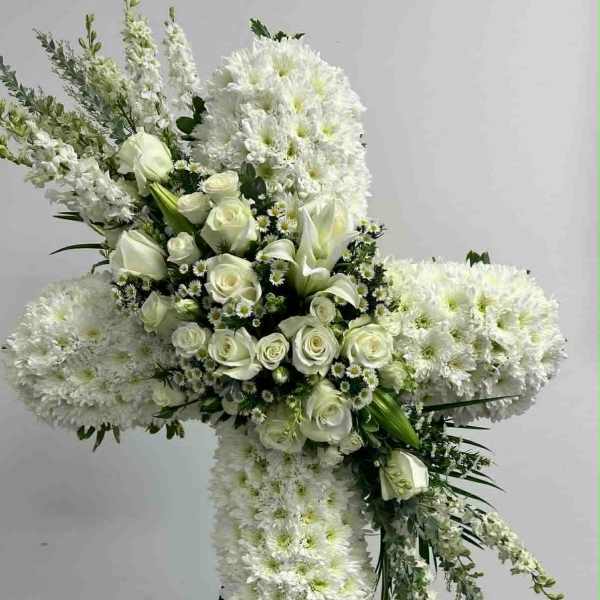 White floral cross on a stand with roses and chrysanthemums
