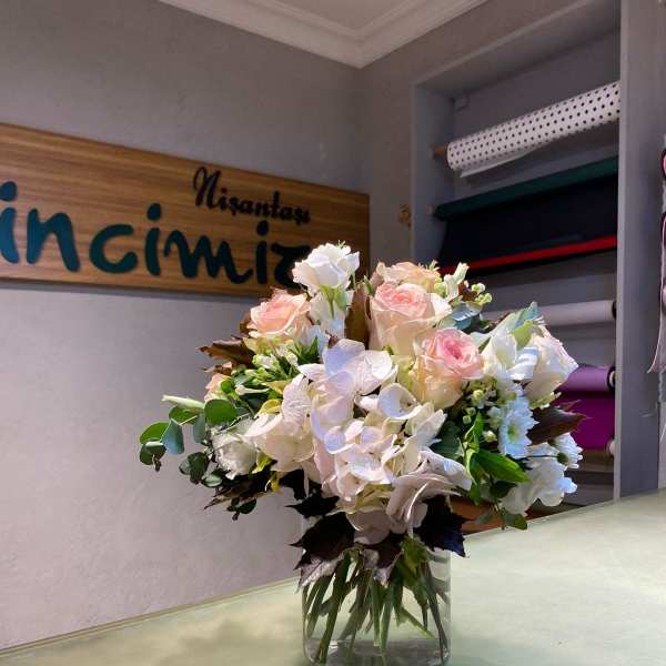 Bouquet of pale pink and white roses in a clear glass vase