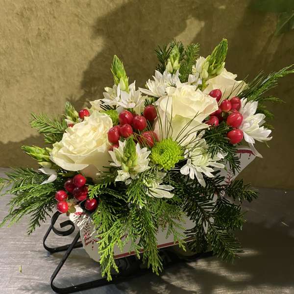 White floral arrangement with red berries in a decorative container