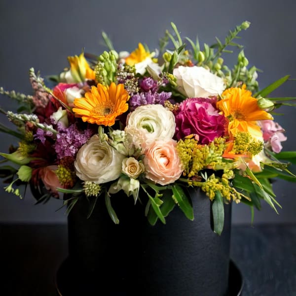 Mixed bouquet in a black hatbox with orange, white, pink, and purple flowers