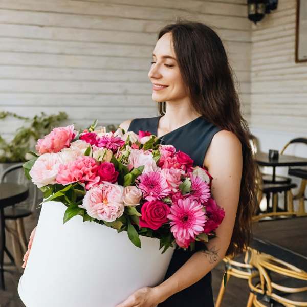Woman holding a large white box filled with pink flowers
