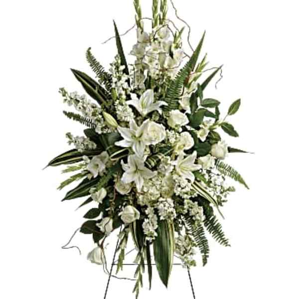 White floral standing spray on an easel with lilies and roses