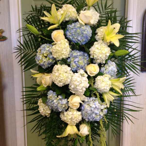 Tall standing floral spray with white lilies, roses, and blue hydrangeas