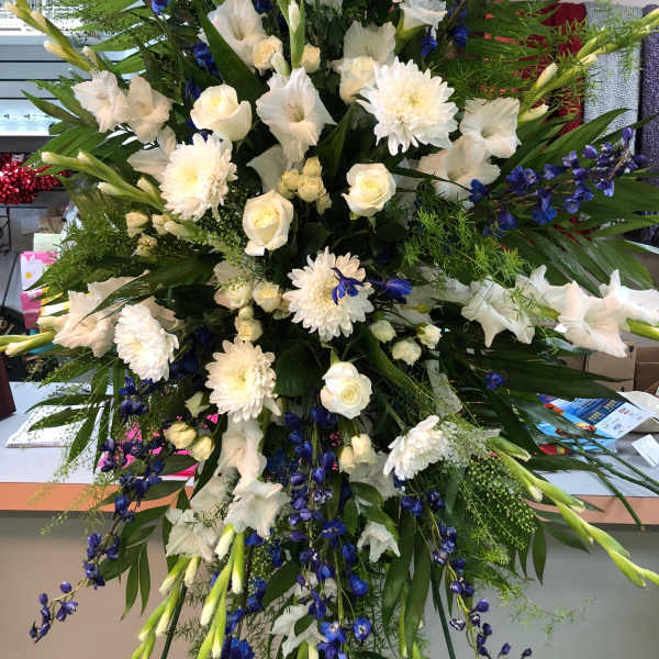 Large standing floral spray with white flowers and blue accents