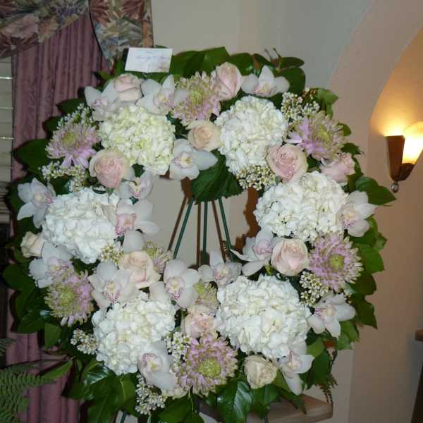 Large floral wreath on an easel with white and pale pink flowers