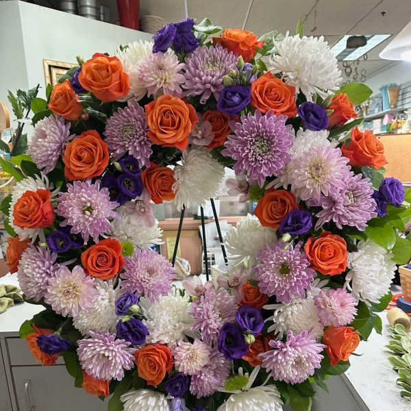 Heart-shaped floral wreath with orange roses, purple blooms, and white chrysanthemums
