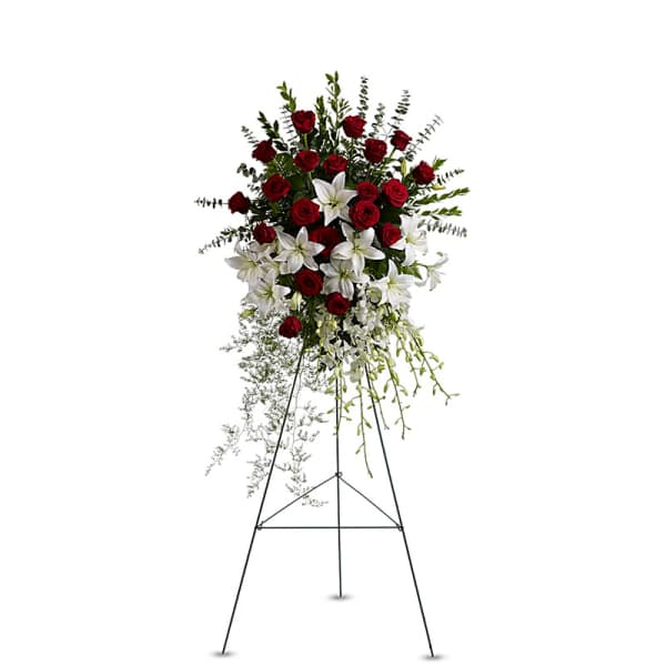 Standing floral spray with red roses and white lilies on an easel