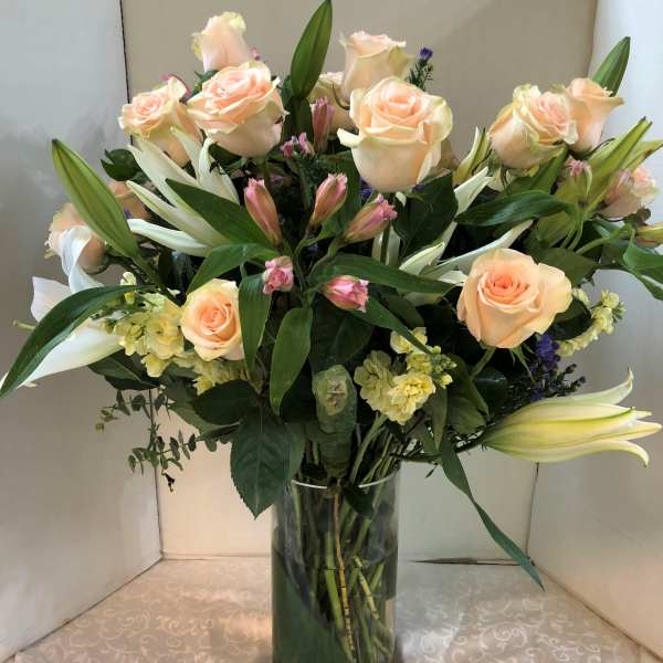 Bouquet of peach roses and white lilies in a glass vase