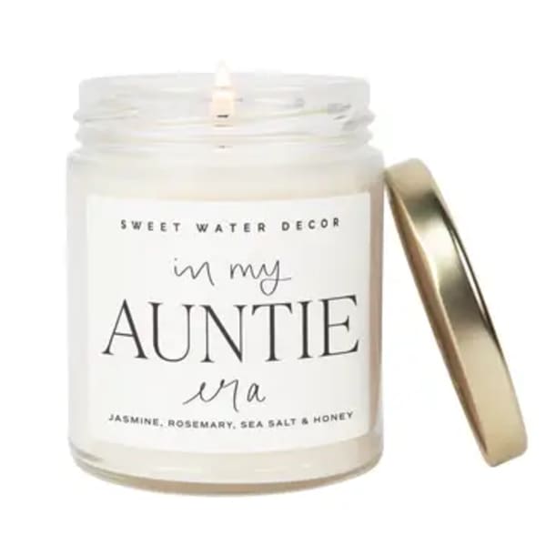 White candle in a glass jar with a gold lid and label for an aunt
