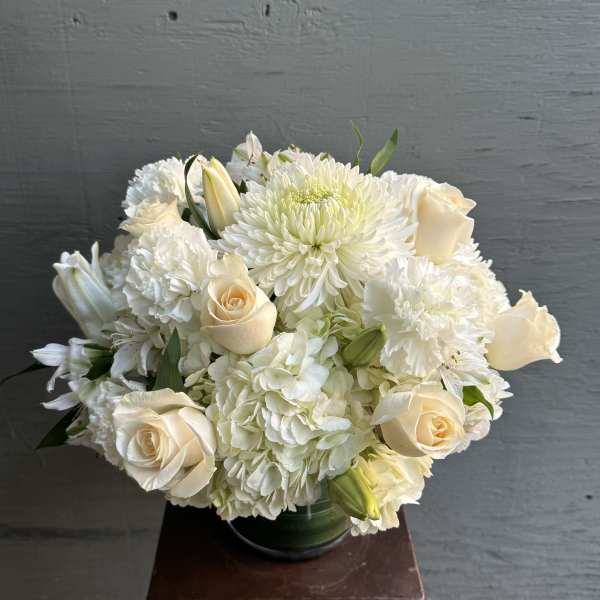 White floral bouquet with cream roses and chrysanthemums in a glass vase