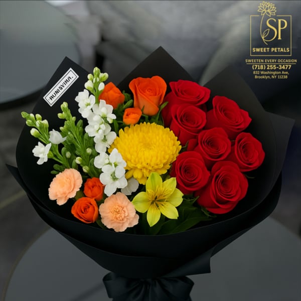 Bouquet of red and orange roses with yellow and white flowers in black wrap