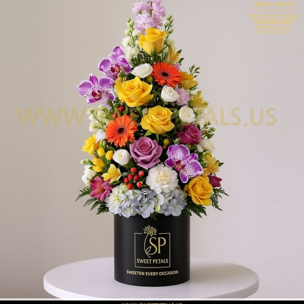 Tall mixed flower arrangement in a black cylindrical box
