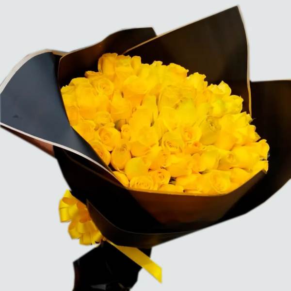 Bouquet of yellow roses wrapped in dark paper with a yellow ribbon