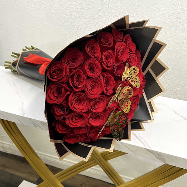 Bouquet of red roses wrapped in black paper with gold butterfly accents