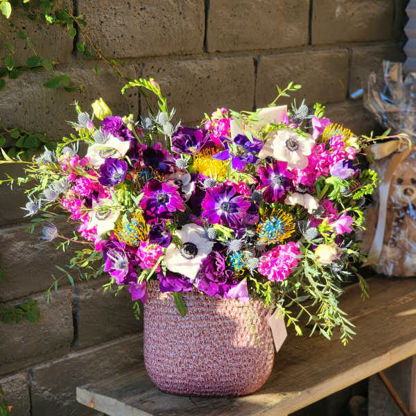 A colorful mixed flower arrangement in a textured vase