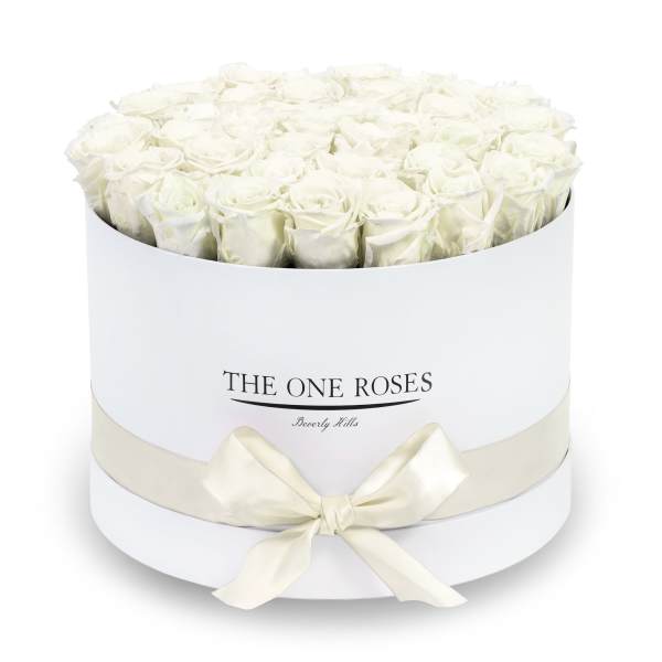 White roses arranged in a round white box with a ribbon bow