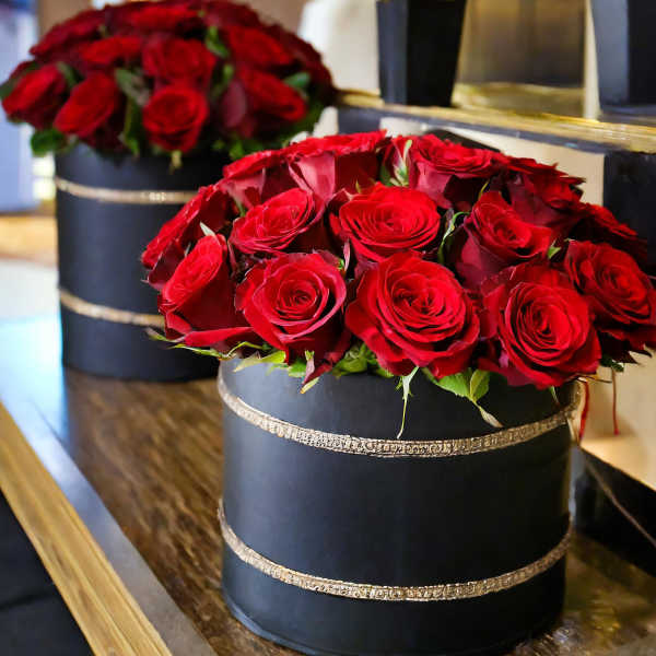 Red roses arranged in black round boxes with gold trim