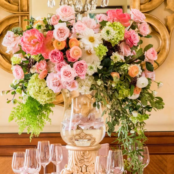 Large pink and white floral centerpiece in a clear vase on a decorated table