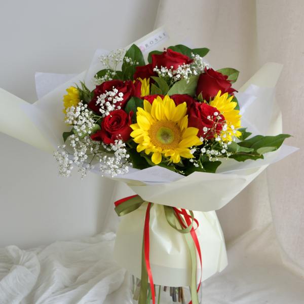 Bouquet of red roses and yellow sunflowers in white wrap