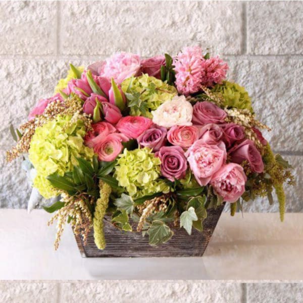 Pink and green mixed flower arrangement in a rectangular wooden container