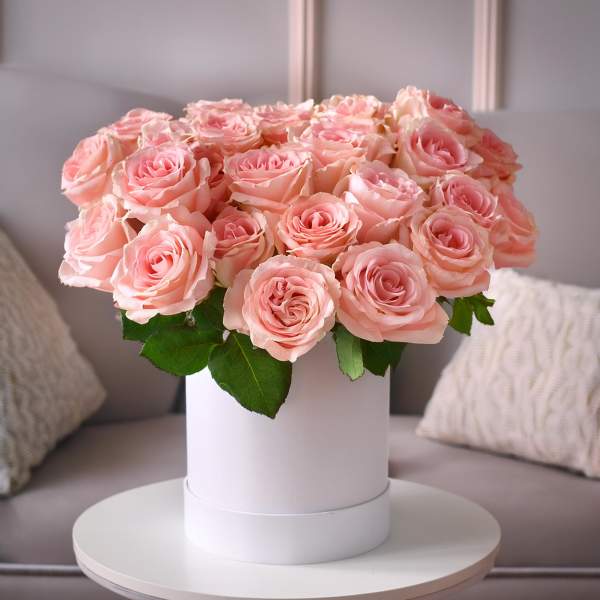 Pink roses arranged in a white hat box on a small table